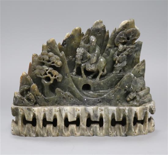 A Chinese soapstone carving depicting travellers crossing a landscape, height 17cm